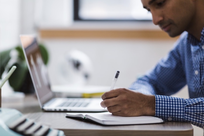 Man writing on notepad. Image by NegativeSpace released via Creative Commons 